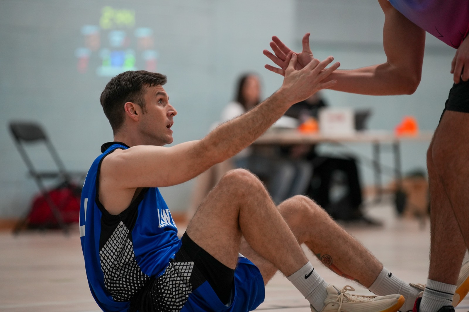A player reaching down to pull a teammate up off the floor