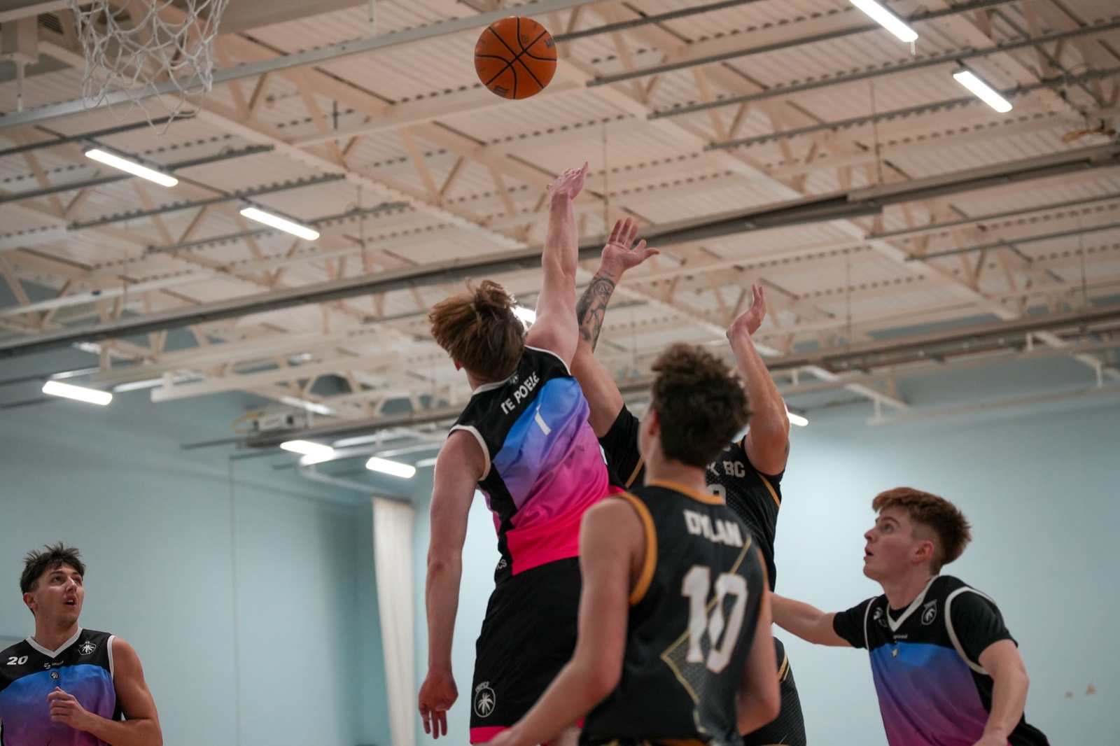 The ball in the air above the rim as players rise to contest it